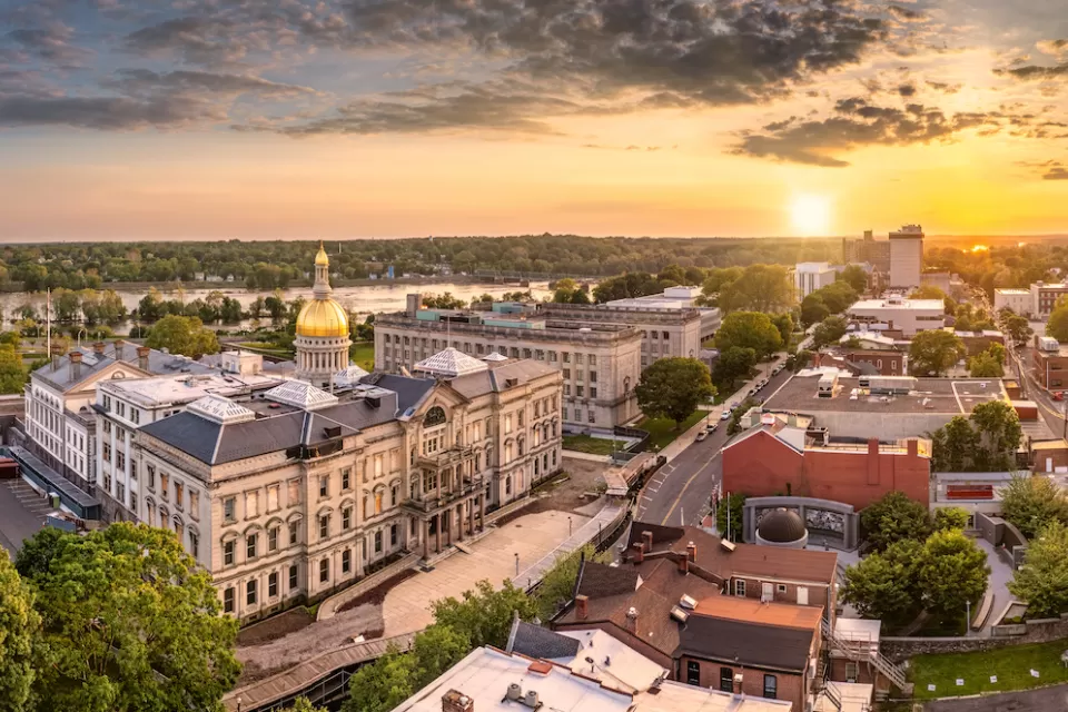 Aerial view of Trenton, New Jersey with gold state capitol down in foreground and golden hour sky.